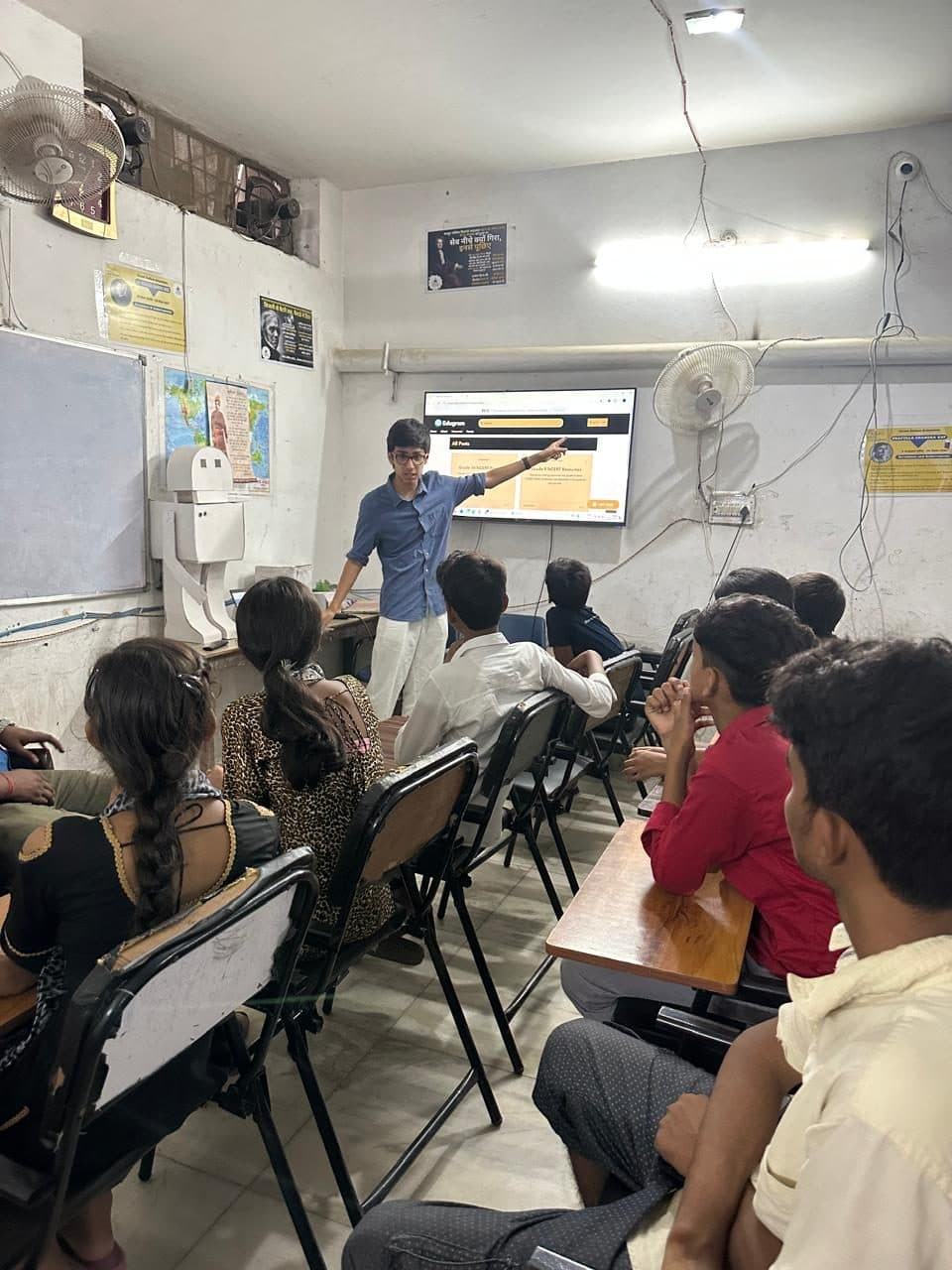 A member of the Edugram team presenting the website on a wall-mounted screen to students seated in Prayatna's classroom.