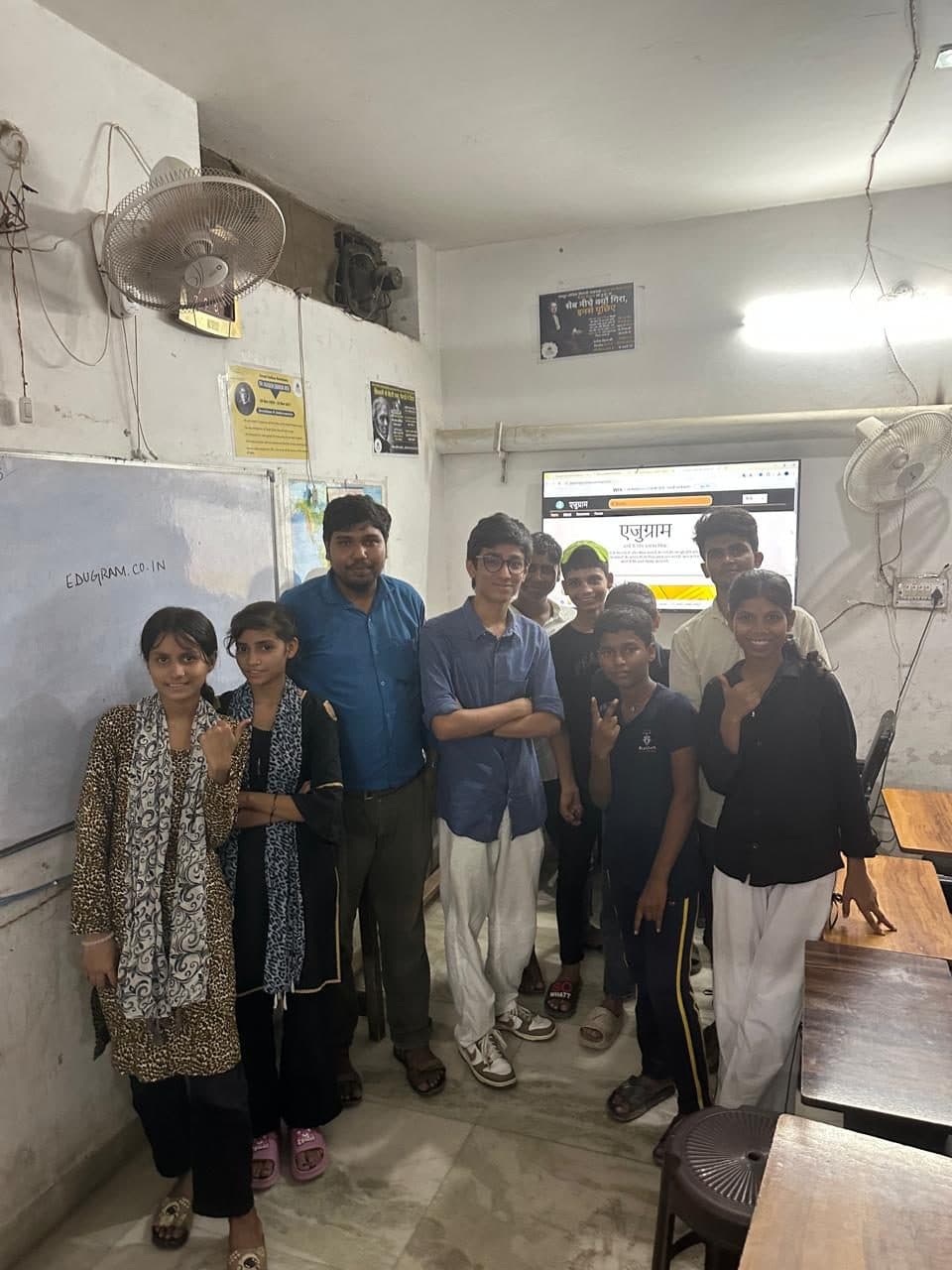 Students and staff at Prayatna gathered for a group photograph in front of the screen showing the Edugram website.
